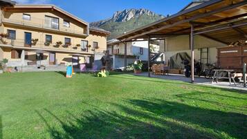 A courtyard with a mountain backdrop, outdoor seating, and a covered area with a motorcycle.