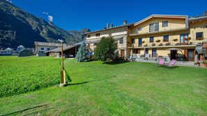 A hotel with a mountain backdrop, a well-maintained lawn, and outdoor seating. - Private room with mountain view, shared terrace and Wi-Fi (Pont-Saint-Martin)