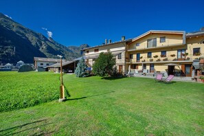 A hotel with a mountain backdrop, a well-maintained lawn, and outdoor seating.