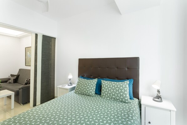 A bedroom with a bed, nightstands, a sofa, and a mirror.