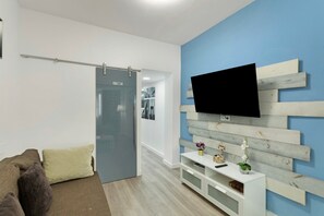 A modern living room with a sofa, a TV mounted on a wooden wall, a sliding door, and a white console table.