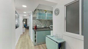 Una cocina moderna con microondas integrado, un lavabo y un refrigerador pequeño.