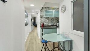 Una cocina moderna con una mesa redonda de vidrio, una silla azul y un salpicadero con diseño.