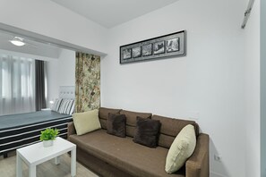 A modern living room with a sofa, a small table with a plant, and a wall-mounted picture frame.