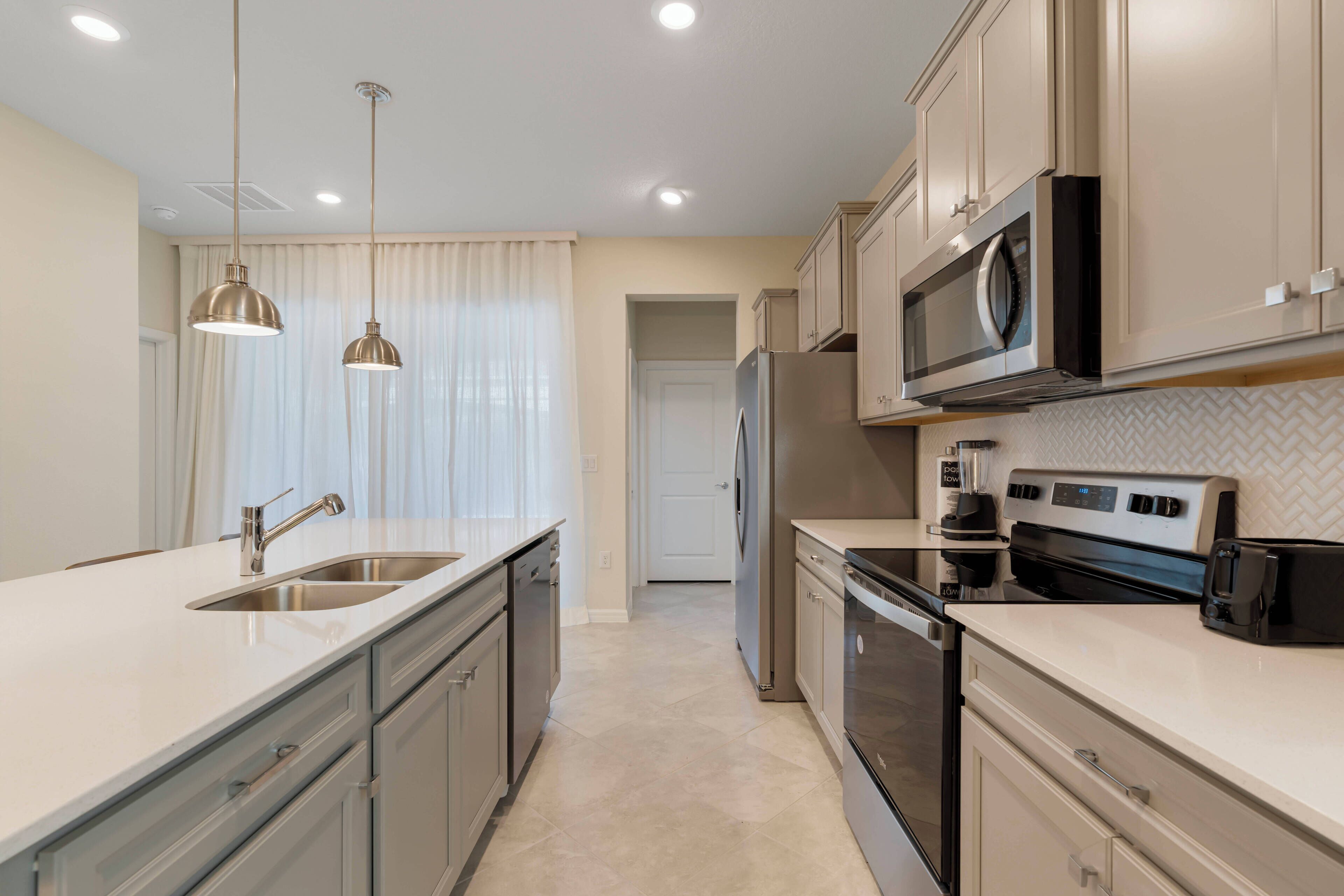 A modern kitchen with stainless steel appliances, a double sink, and pendant lighting.