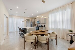 Una cocina moderna con comedor, que incluye una mesa redonda, sillas e iluminación colgante.