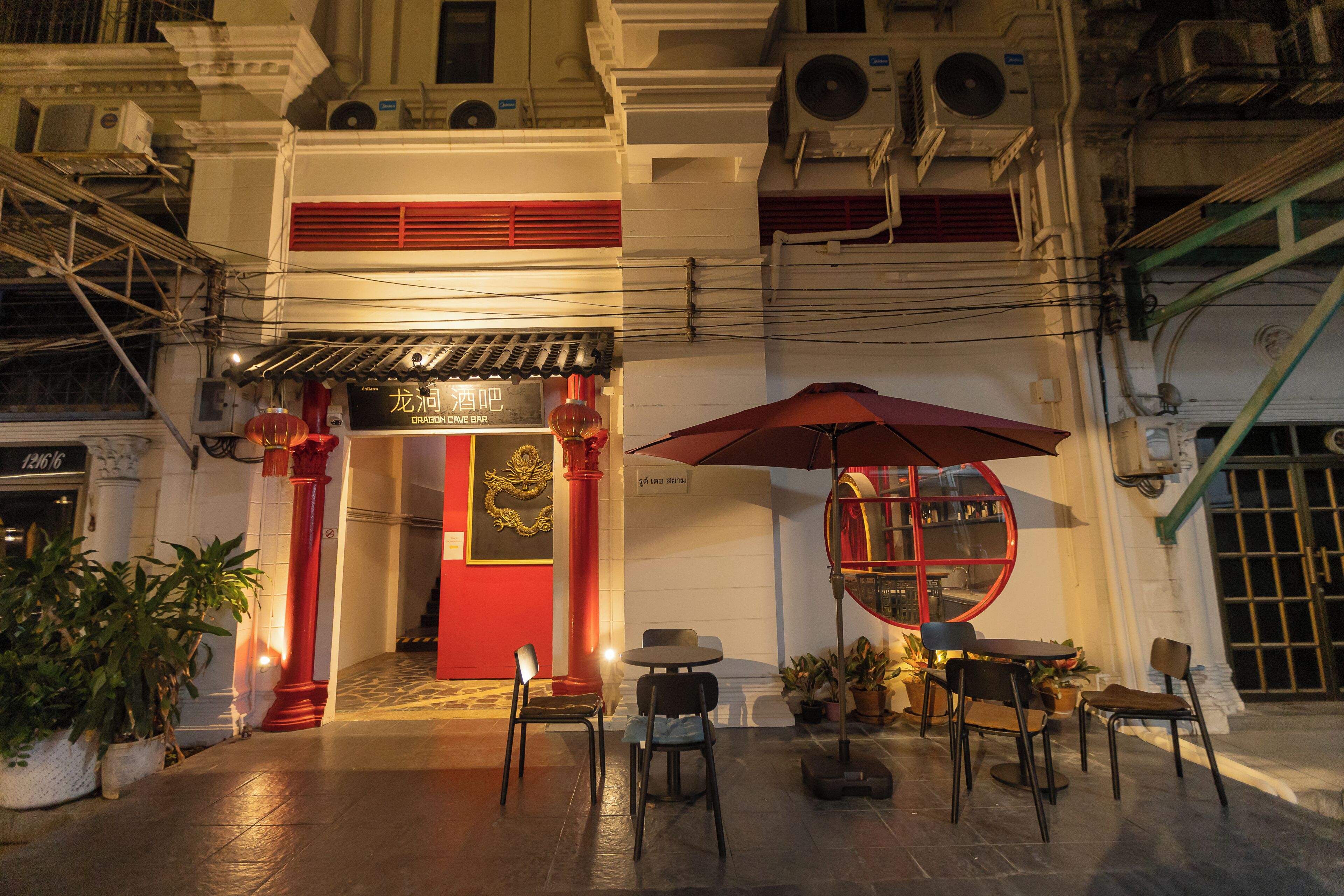 A traditional building with a red entrance, outdoor seating area, and potted plants.