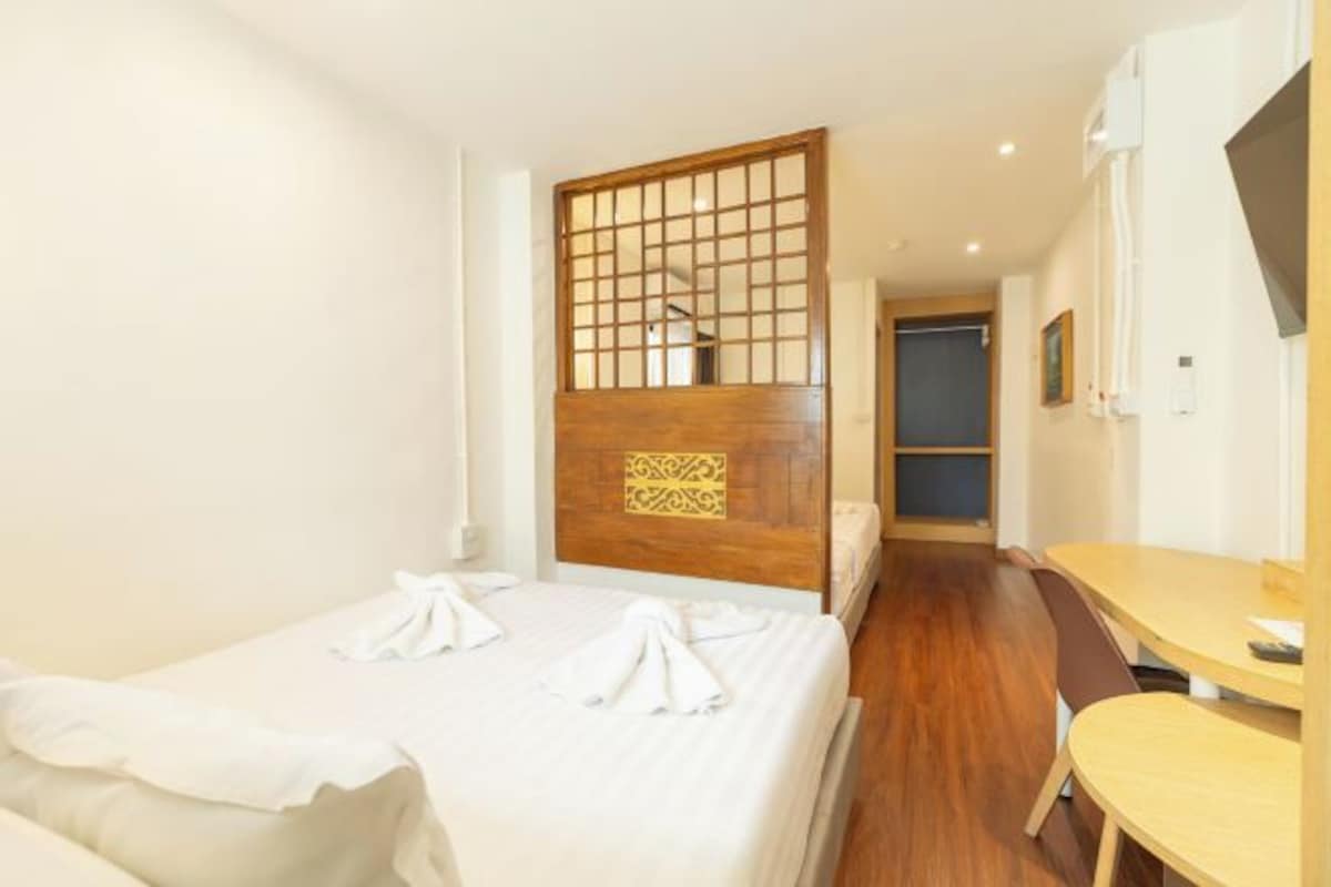 Una habitación de hotel con cama, un separador de madera, un escritorio y una silla.