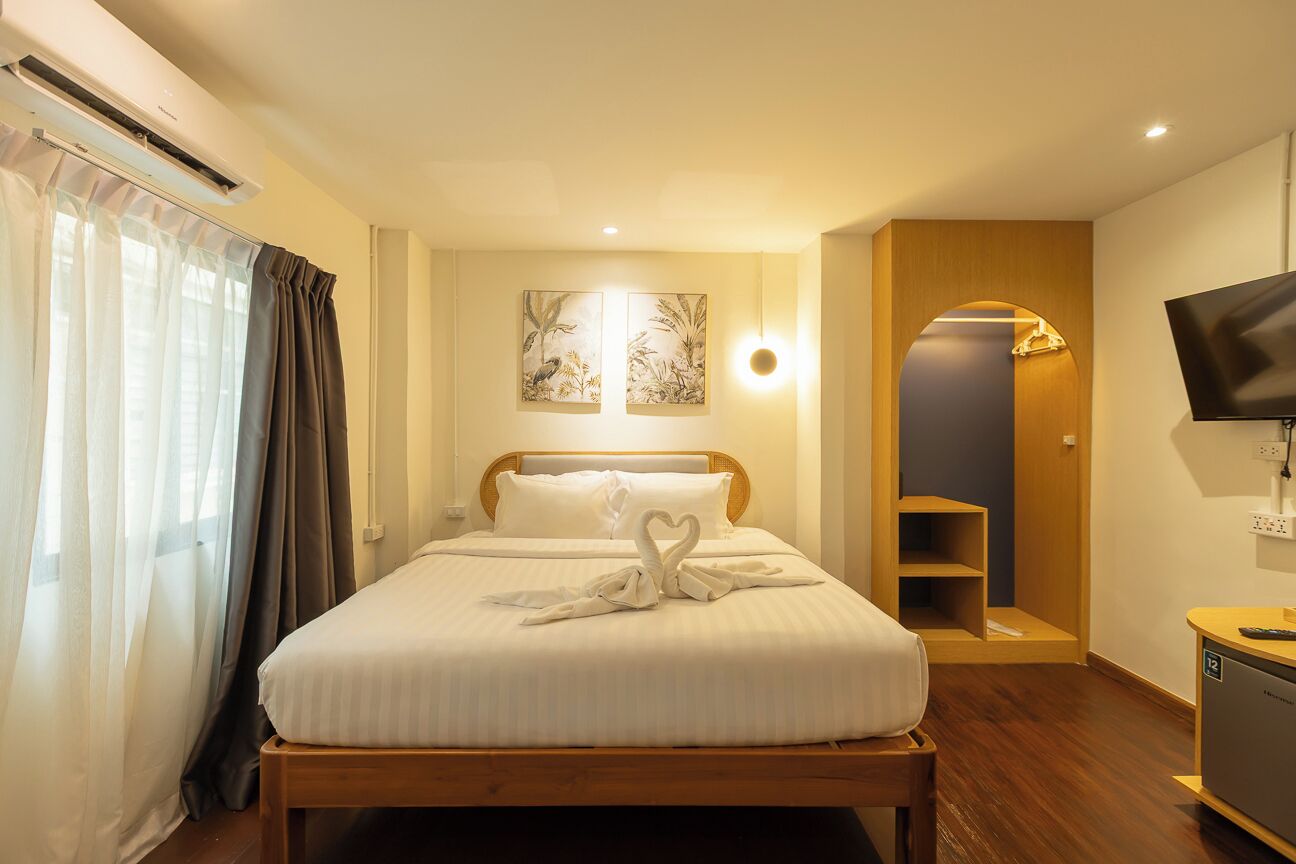A hotel room with a bed, a television, a desk, and a wall-mounted artwork.