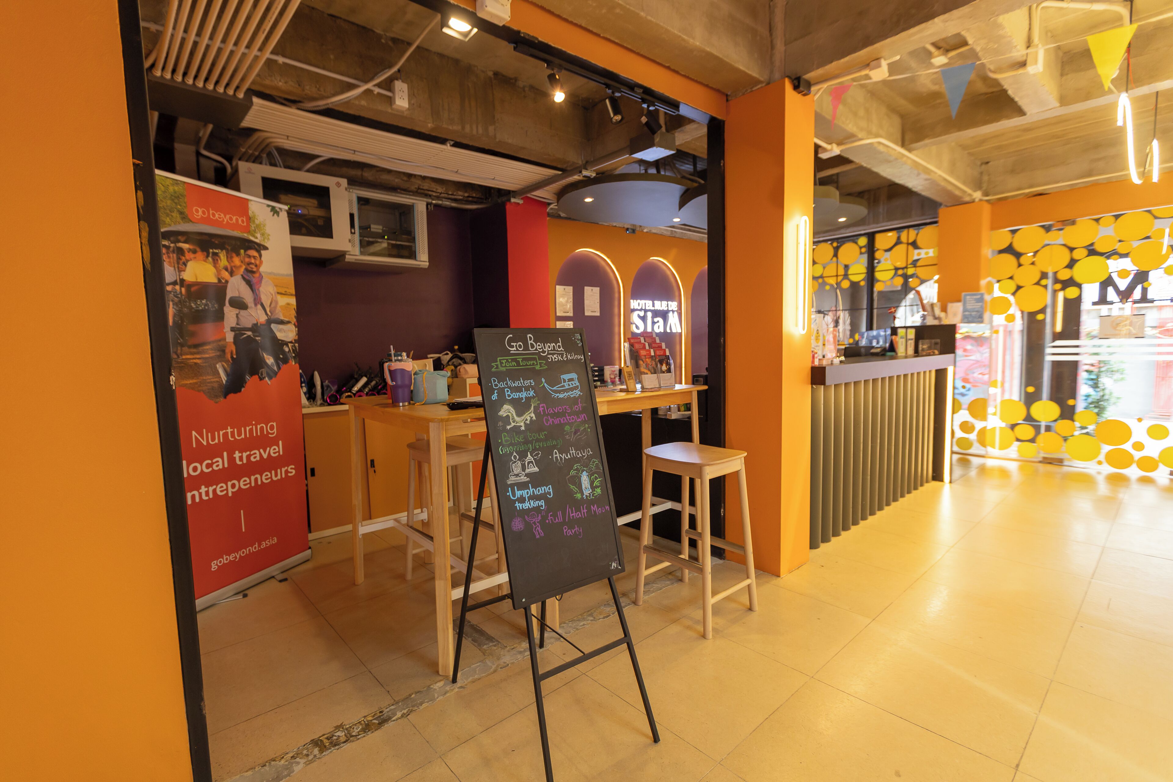A restaurant interior with a chalkboard menu, wooden tables, and a colorful wall design.
