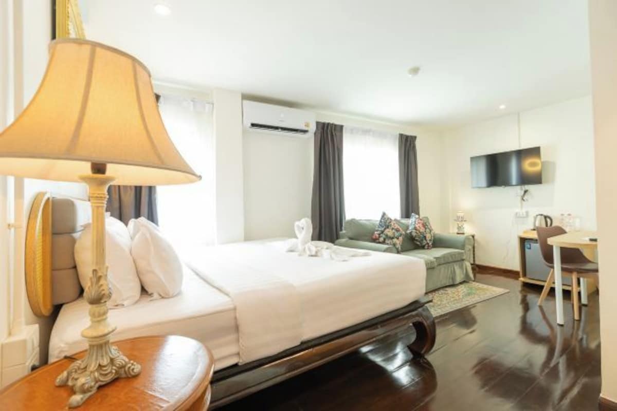 Una habitación de hotel con cama, escritorio, televisor y aire acondicionado.