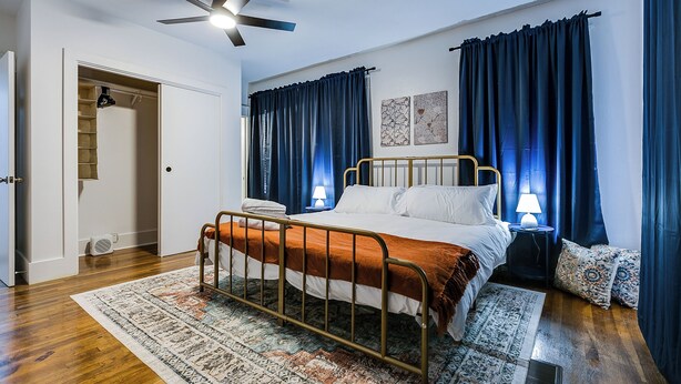 A bedroom with a bed, a ceiling fan, a nightstand with a lamp, and a patterned rug. - Timeless Getaway in San Angelo! Fully renovated 3BR/2BA 1920s Home (San Angelo)