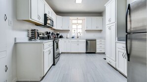 A modern kitchen with white cabinetry, stainless steel appliances, and a central island. - Timeless Getaway in San Angelo! Fully renovated 3BR/2BA 1920s Home (San Angelo)
