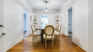 A dining area with a wooden table and chairs, white walls, and a ceiling light. - Timeless Getaway in San Angelo! Fully renovated 3BR/2BA 1920s Home (San Angelo)