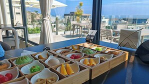 A breakfast buffet with various food items in wooden compartments, set on a table with a view of the city through large windows. - YOOOO SEA TRUE REST HOTEL (Fuzhou)