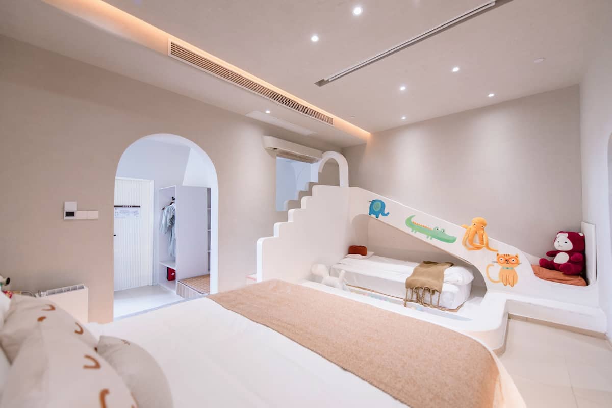 A modern bedroom with a large bed, a built-in desk, and a staircase with playful animal decorations.