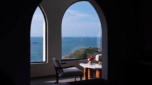 A room with a large arched window overlooking a coastal area with wind turbines. - YOOOO SEA TRUE REST HOTEL (Fuzhou)