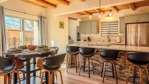 Une cuisine moderne avec un îlot central, des tabourets de bar et des poutres en bois au plafond.