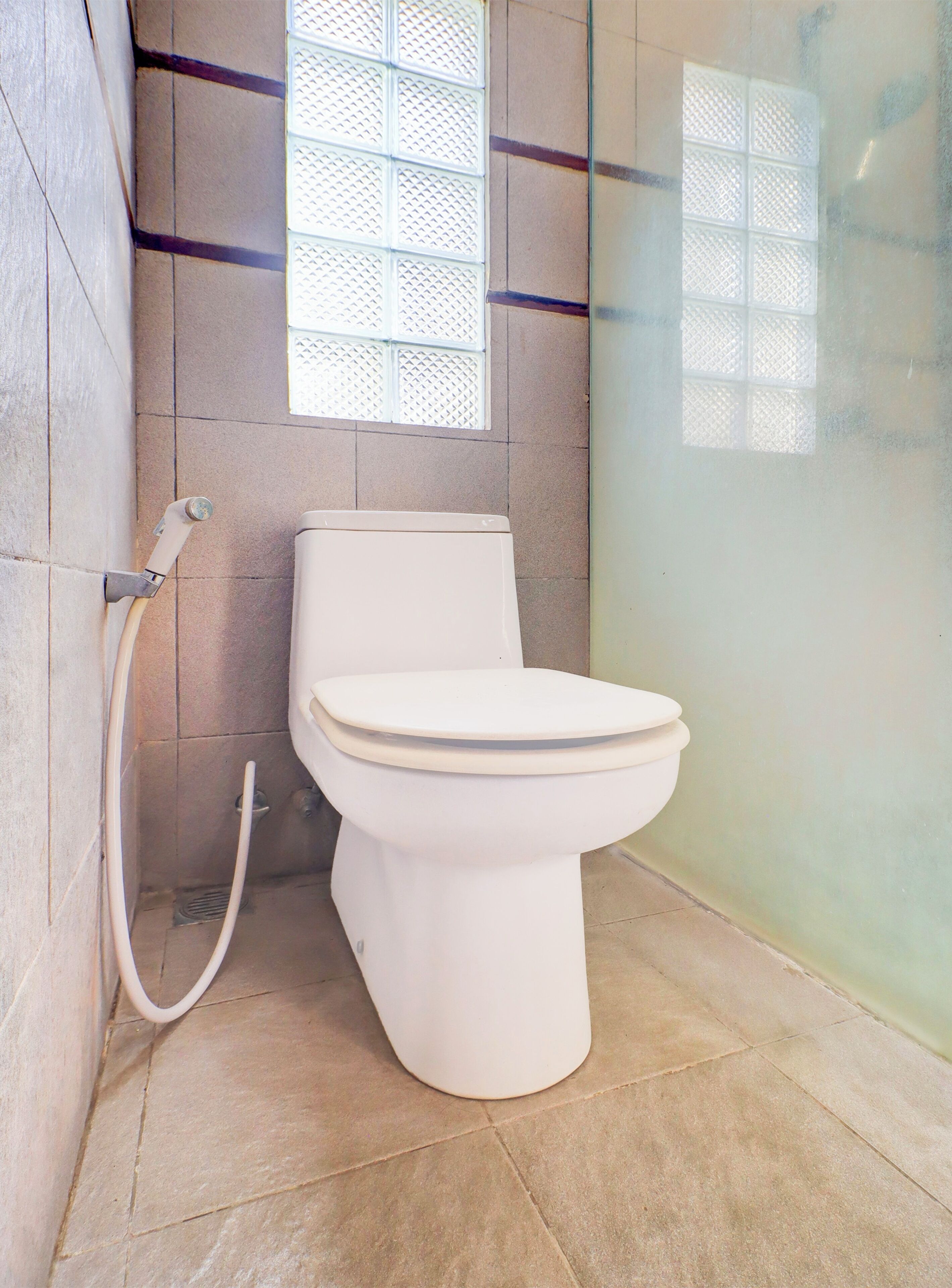 Une salle de bain équipée de toilettes, d’une douche et d’une cabine de douche en verre dépoli.