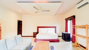 A hotel room with a bed, a sofa, a TV, and an air conditioning unit. - Collection O Putri Inn Homestay (Denpasar)