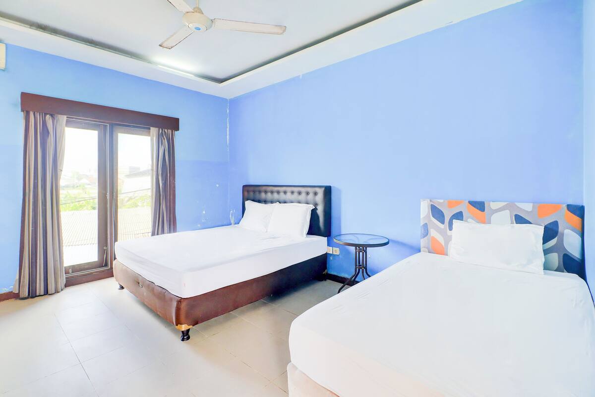 A hotel room with two beds, a ceiling fan, and a balcony view.