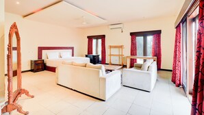 A hotel room with a bed, two sofas, a wooden dresser, a mirror, and a TV. - Collection O Putri Inn Homestay (Denpasar)