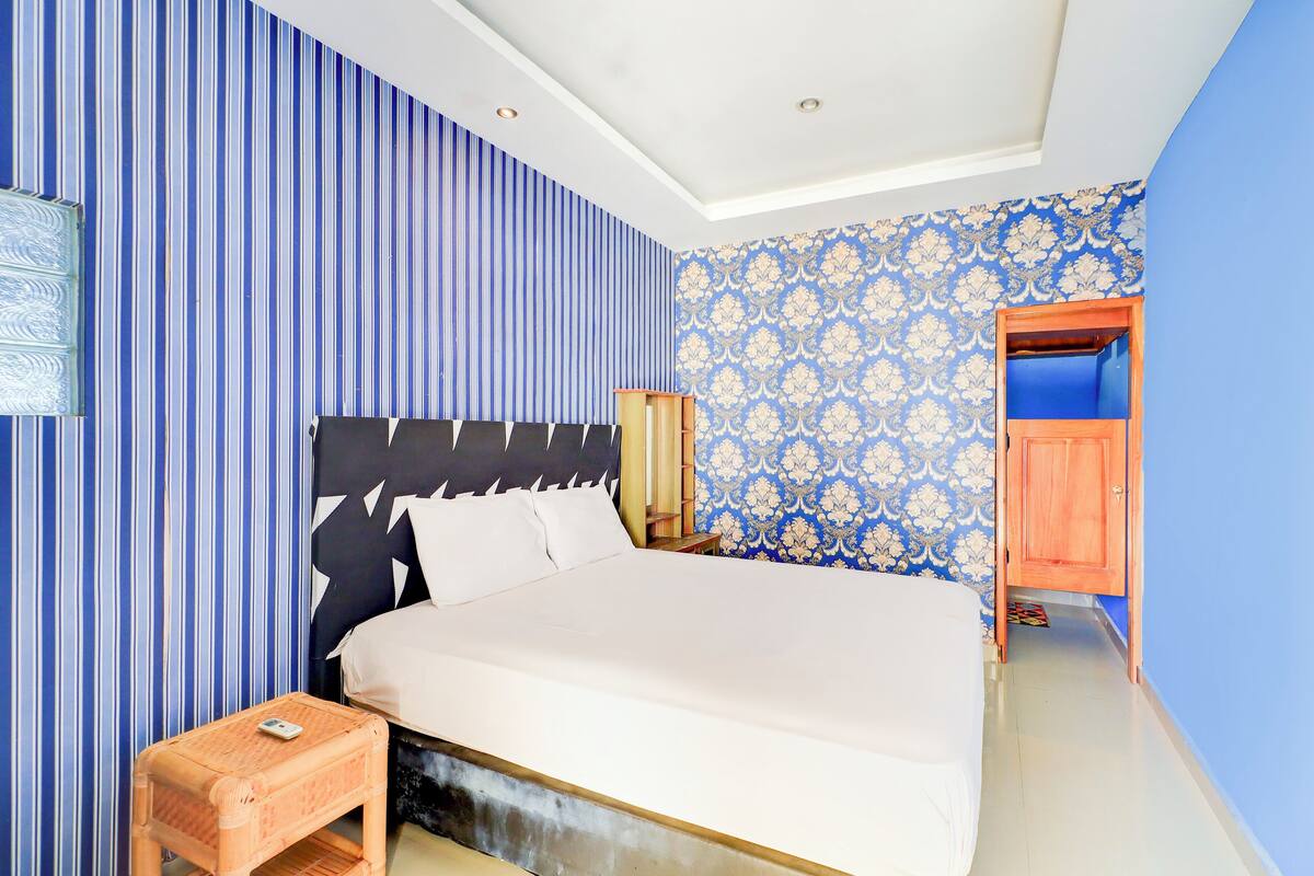 A bedroom with a bed, a nightstand, and a wooden cabinet.