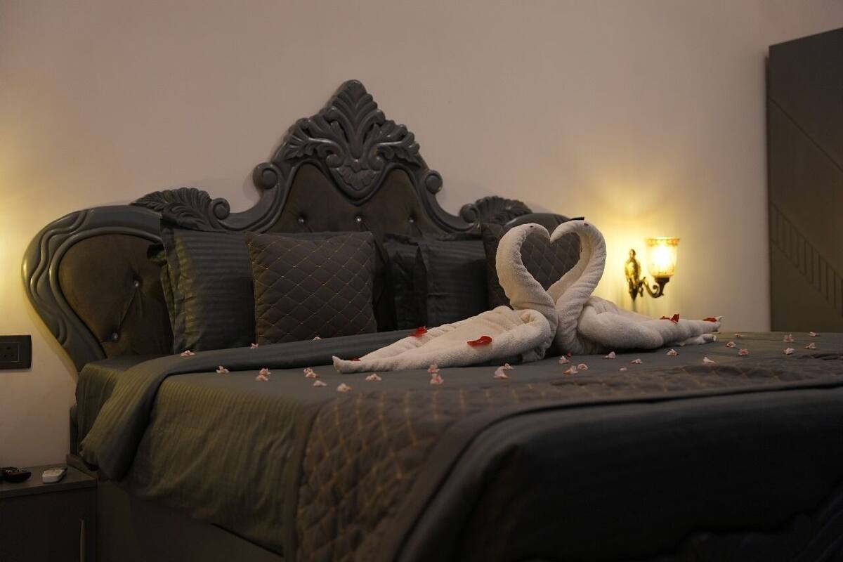 A bed with a dark headboard, pillows, and a blanket.