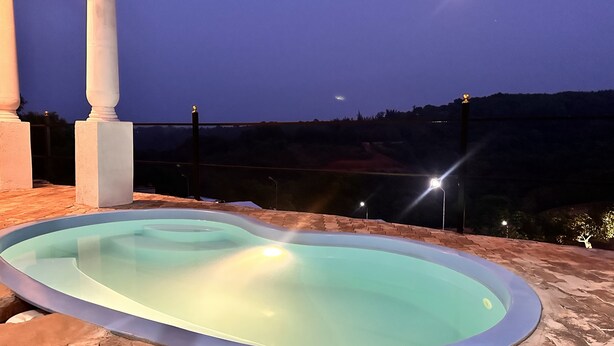 Una piscina al aire libre con vistas a las montañas al atardecer.