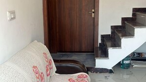 Ein Zimmer mit einer Couch, einer Holztür mit Nummernschild und einer Treppe.