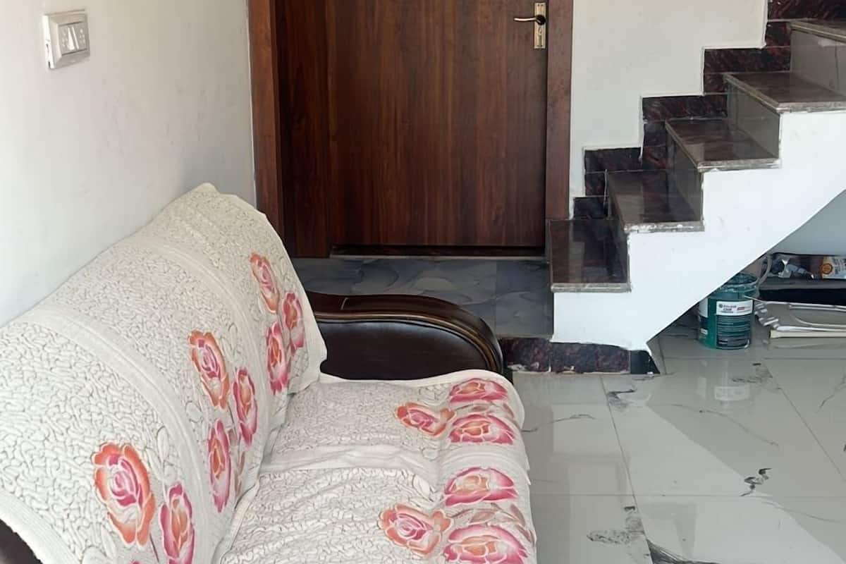 Ein Zimmer mit einer Couch, einer Holztür mit Nummernschild und einer Treppe.