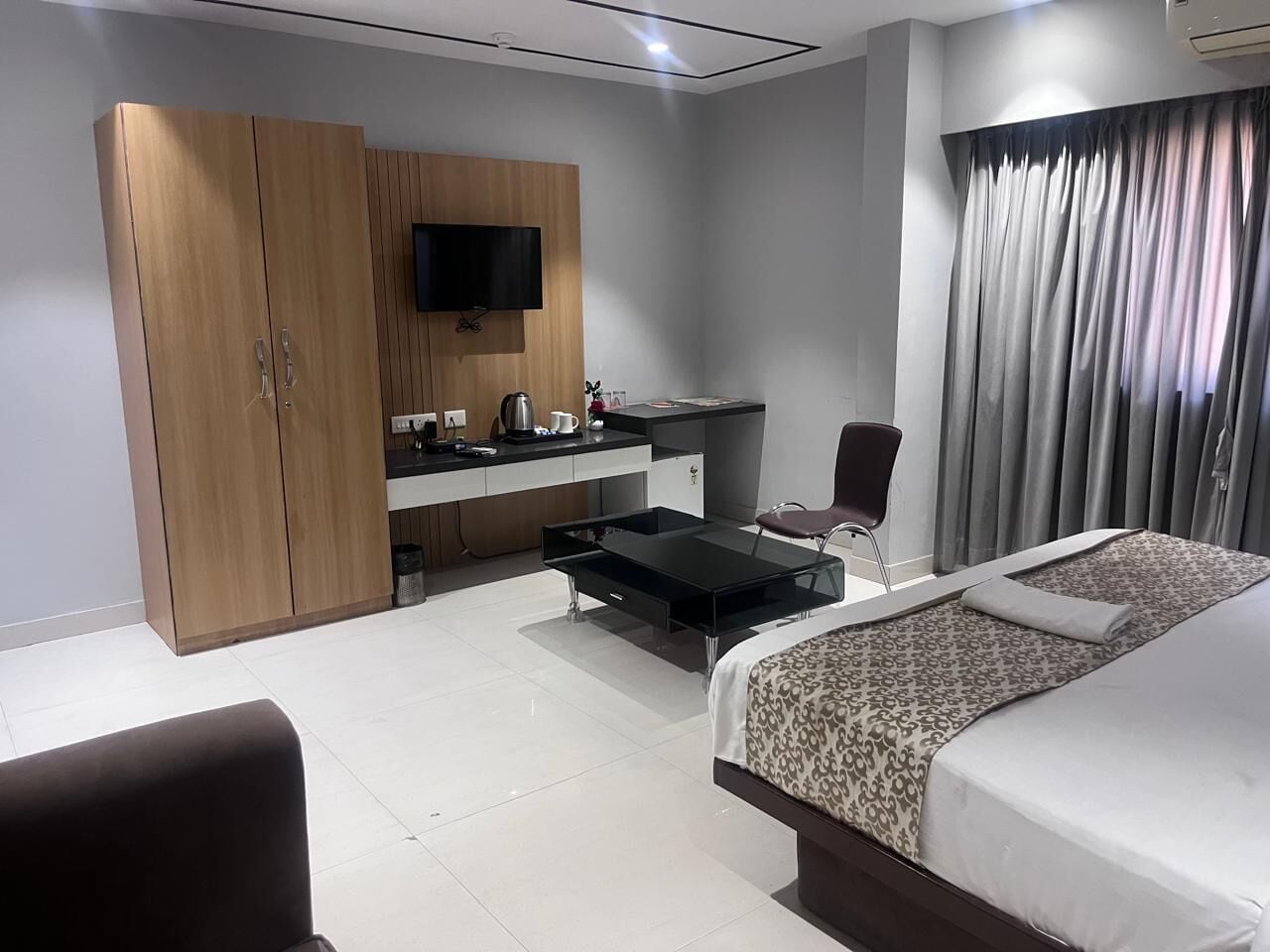 Una habitación de hotel moderna con una cama, un escritorio con una silla, un armario y un televisor.