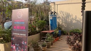 A covered outdoor area with a sign for 'Raipur Social Kitchen & Bar' open from 11:00 AM to 11:59 PM.