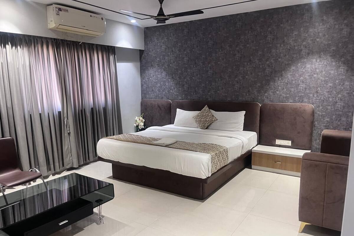 A modern bedroom with a large bed, a glass coffee table, a desk, and a chair.