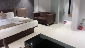 A modern bedroom with a bed, a sofa, a wardrobe, and a small table.