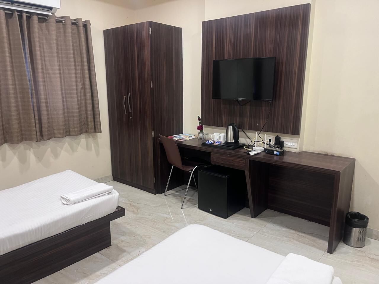 Habitación de hotel con cama, escritorio, computadora, televisor y armario.