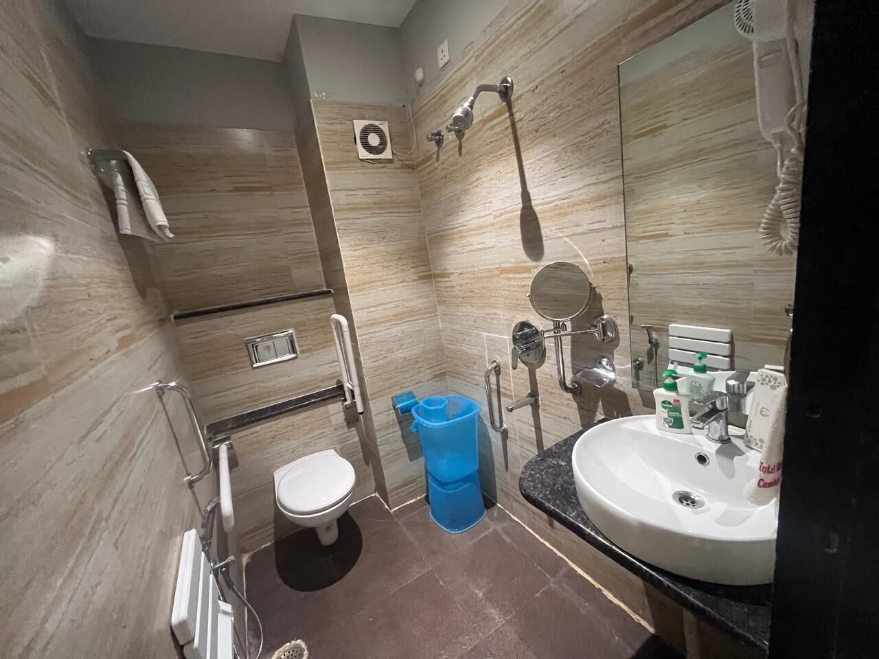 A modern bathroom with a white toilet, a sink with a mirror, and a shower area.