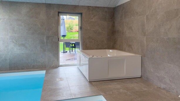 A modern bathroom with a bathtub, a shower, and a glass-enclosed pool area. - Lovely home in Ebeltoft (Ebeltoft)