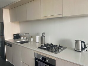 A modern kitchen with stainless steel appliances, a sink, and a kettle.