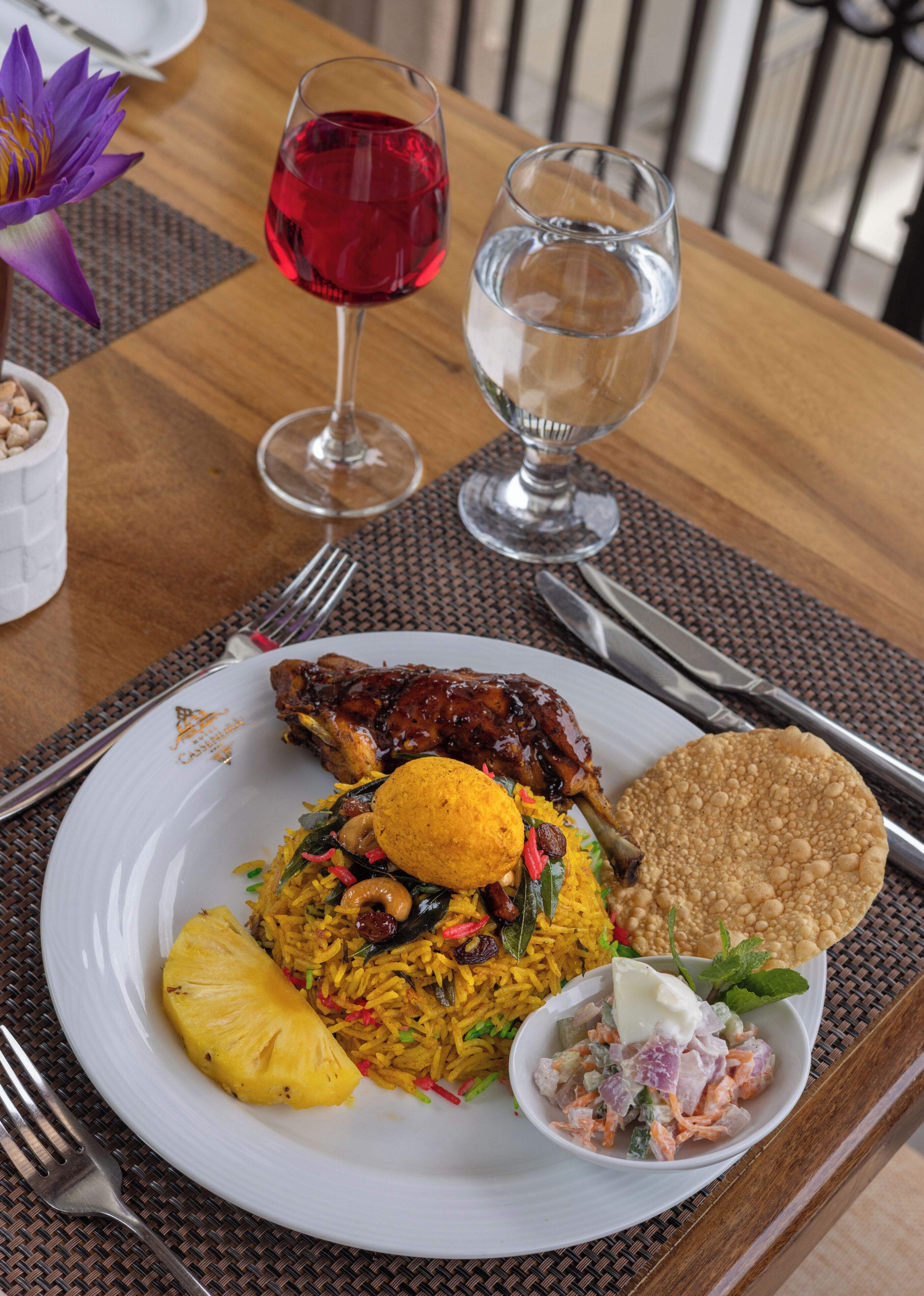 Un plato de comida con arroz, un trozo de carne, algo frito y un bol pequeño de ensalada.