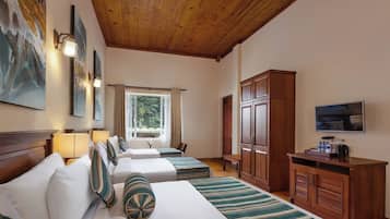 A hotel room with two beds, a TV, wooden cabinets, and artwork on the walls.