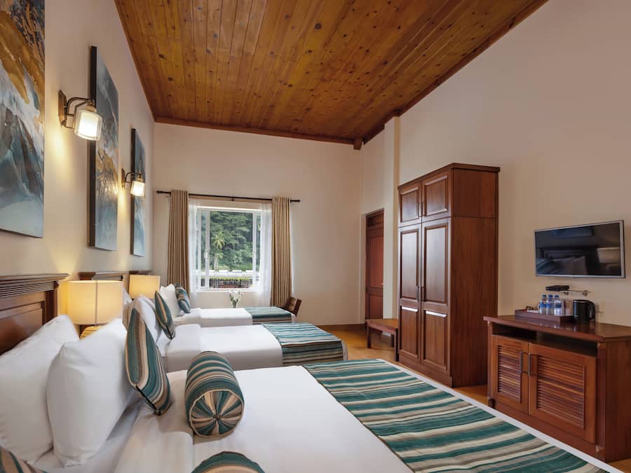 Habitación de hotel con dos camas, un televisor, muebles de madera y obras de arte en las paredes.