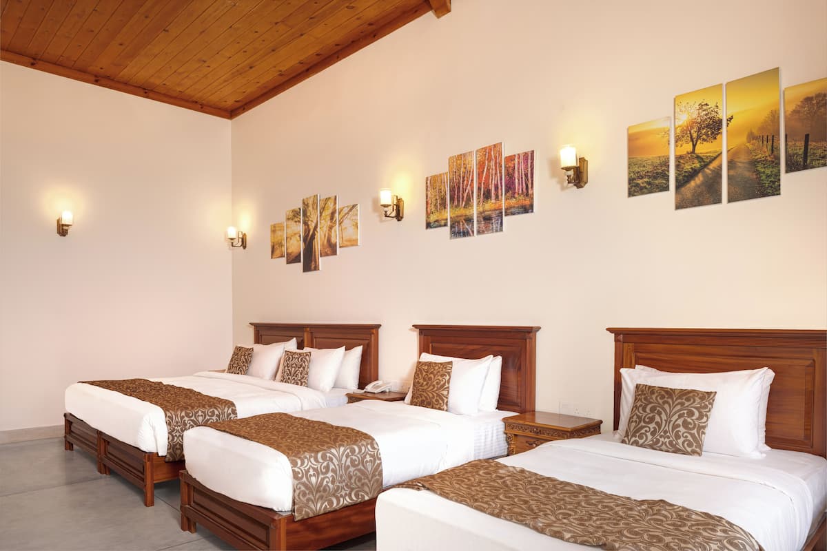 Habitación de hotel con cuatro camas individuales, cabeceros de madera y un cuadro grande colgado en la pared.