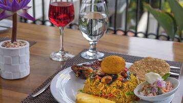 A table with a plate of food, two glasses of water, and a flower vase.