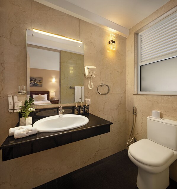 A modern bathroom with a large mirror, a white sink, a towel rack, and a toilet.