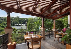 An outdoor patio with a wooden pergola, tables set for dining, and potted plants. - Cassendra Kandy (Kandy)
