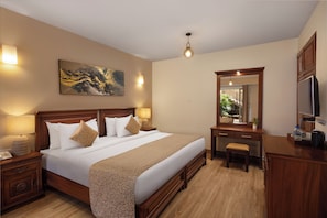 Habitación de hotel con una cama grande, lámparas de noche, un escritorio con espejo y televisión.