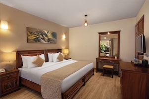 Habitación de hotel con una cama grande, lámparas de noche, un escritorio con espejo y televisión.