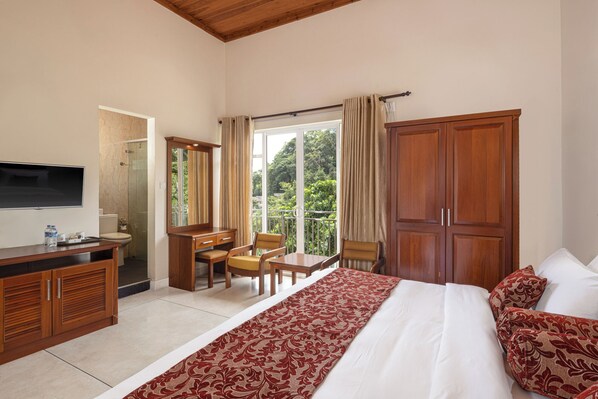 A hotel room with a bed, a desk with a chair, a TV, a wardrobe, and a balcony with curtains.