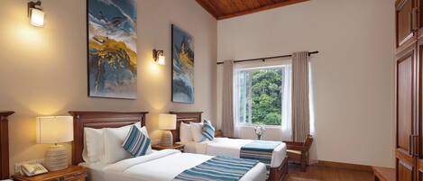 Une chambre d’hôtel avec deux lits, un plafond en bois, une fenêtre avec des rideaux et des œuvres d’art accrochées aux murs.